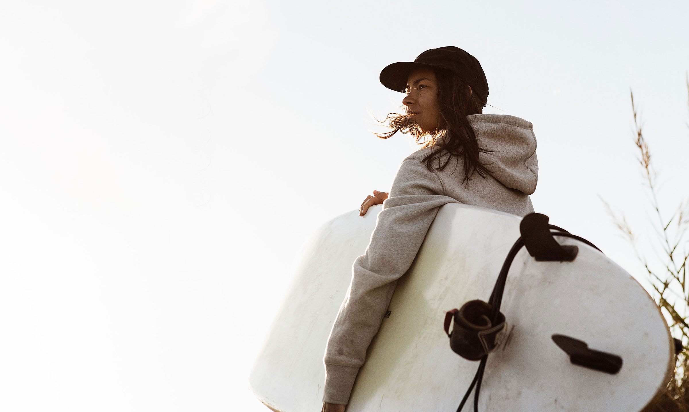Tjej bär surfbräda till stranden i portugal